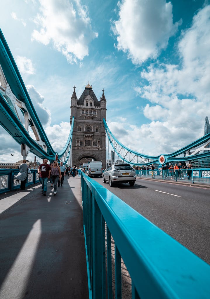 Tower Bridge in London with pedestrians and vehicles, under a bright blue sky.