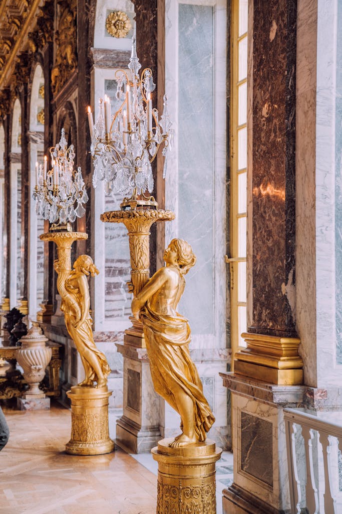 A stunning view of the Hall of Mirrors featuring gilded statues and chandeliers in Versailles, France.