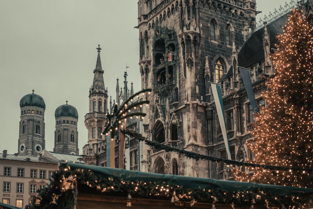 Christmas market at Marienplatz with Munich's historical buildings in the background, showcasing festive lights.