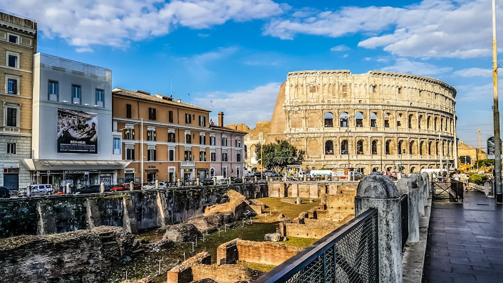 Daylight view of the historic Colosseum in Rome with vibrant city buildings.