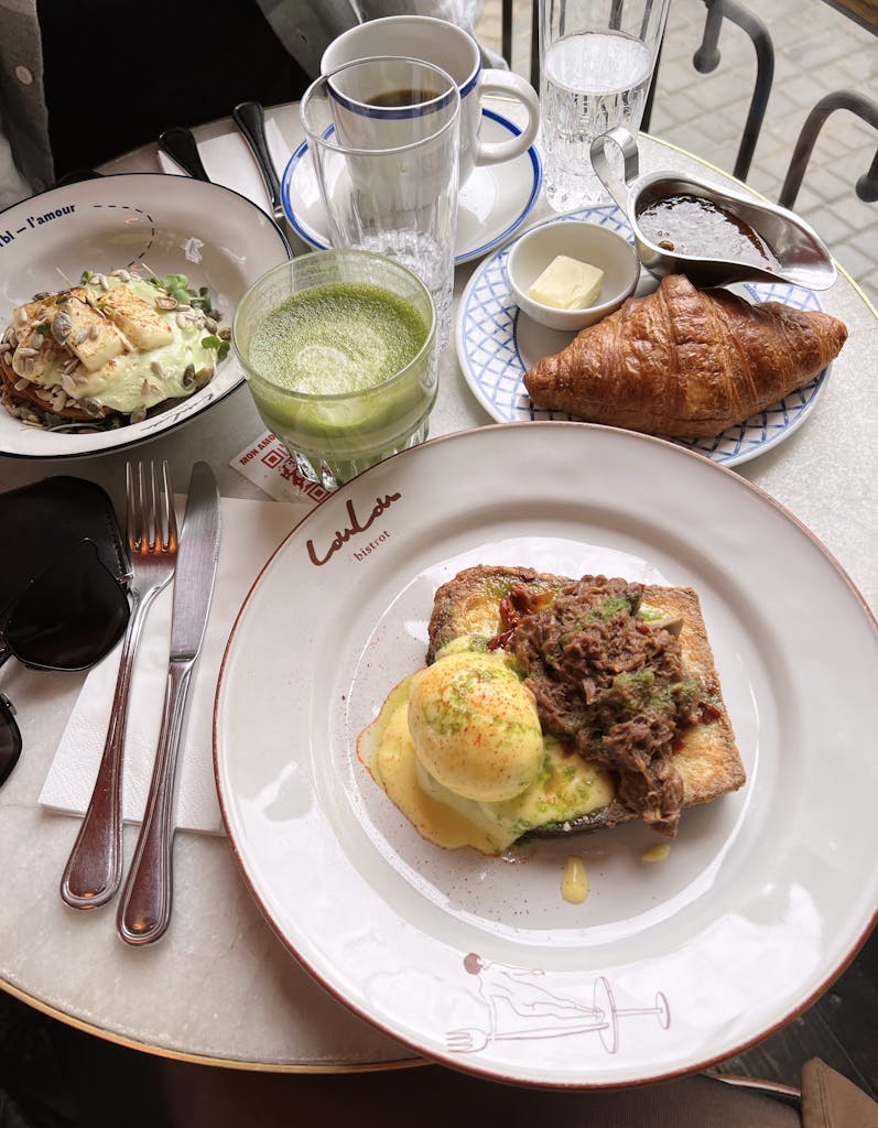 Delicious gourmet breakfast including avocado toast, eggs benedict, and a fresh croissant served elegantly.