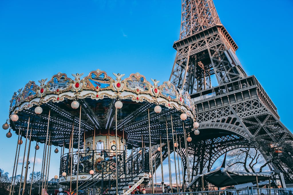 Eiffel Tower with a classic carousel in foreground on a bright day in Paris, France.