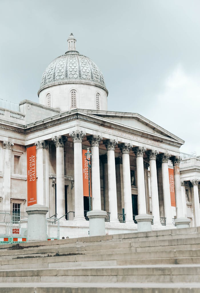 Front view of the National Gallery in London, showcasing its iconic architecture against a cloudy sky.