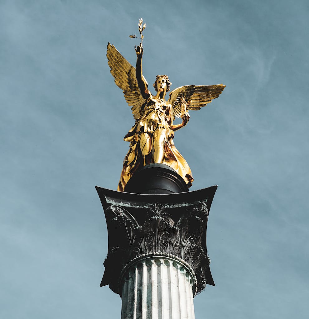 Golden angel sculpture atop Victory Column with a clear sky in Munich.