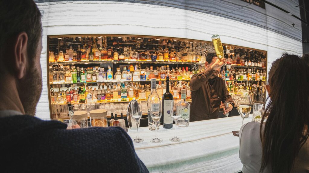 customers watching the bartender preparing a cocktail