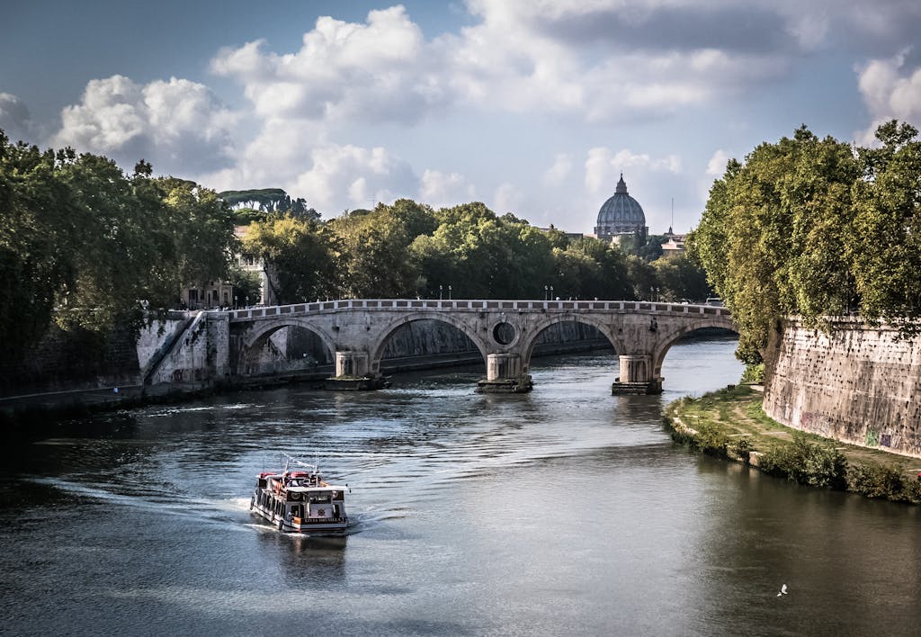 Picturesque scene of Ponte Sant'Angelo and St. Peter's Basilica along the Tiber River in Rome.