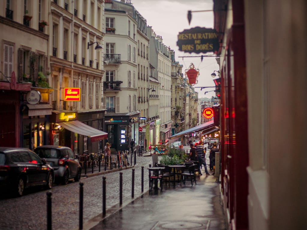 Quaint Parisian street on a rainy day with vintage buildings and cobblestone path.