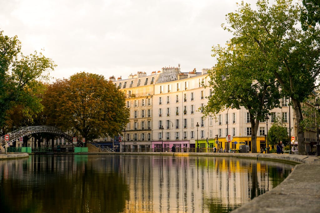 Scenic view of Canal Saint-Martin in Paris with footbridge and colorful buildings reflecting in the water.