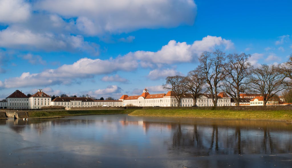 Stunning view of Nymphenburg Palace reflecting on the lake under a bright winter sky in Munich.