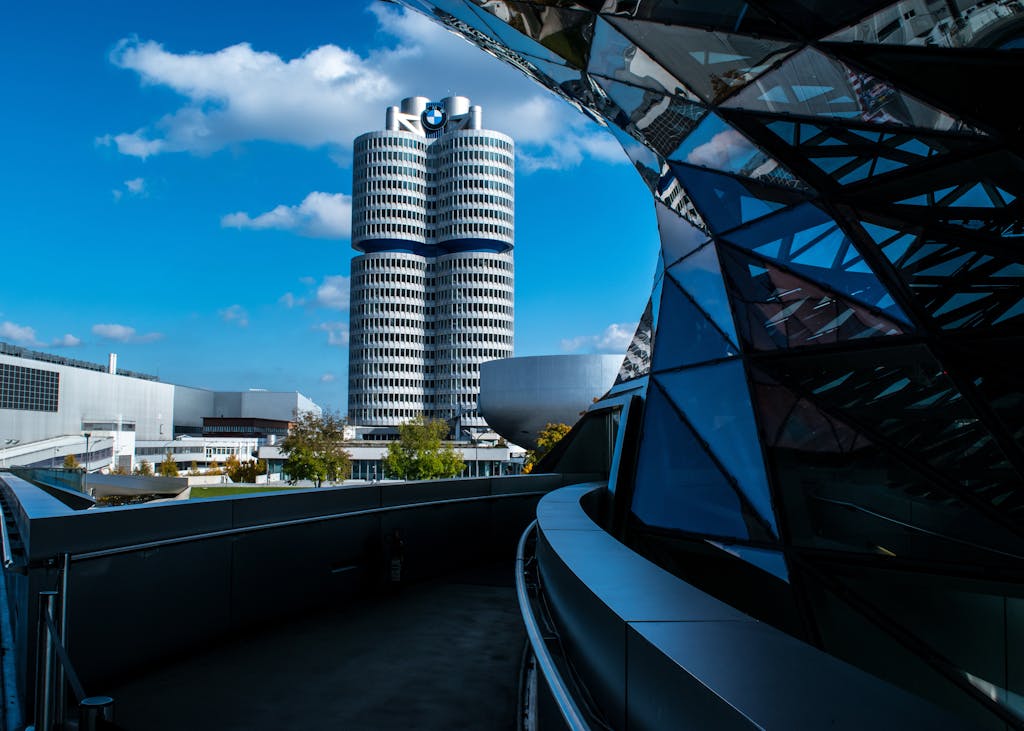 View of BMW headquarters with reflective modern architecture under a vibrant blue sky.